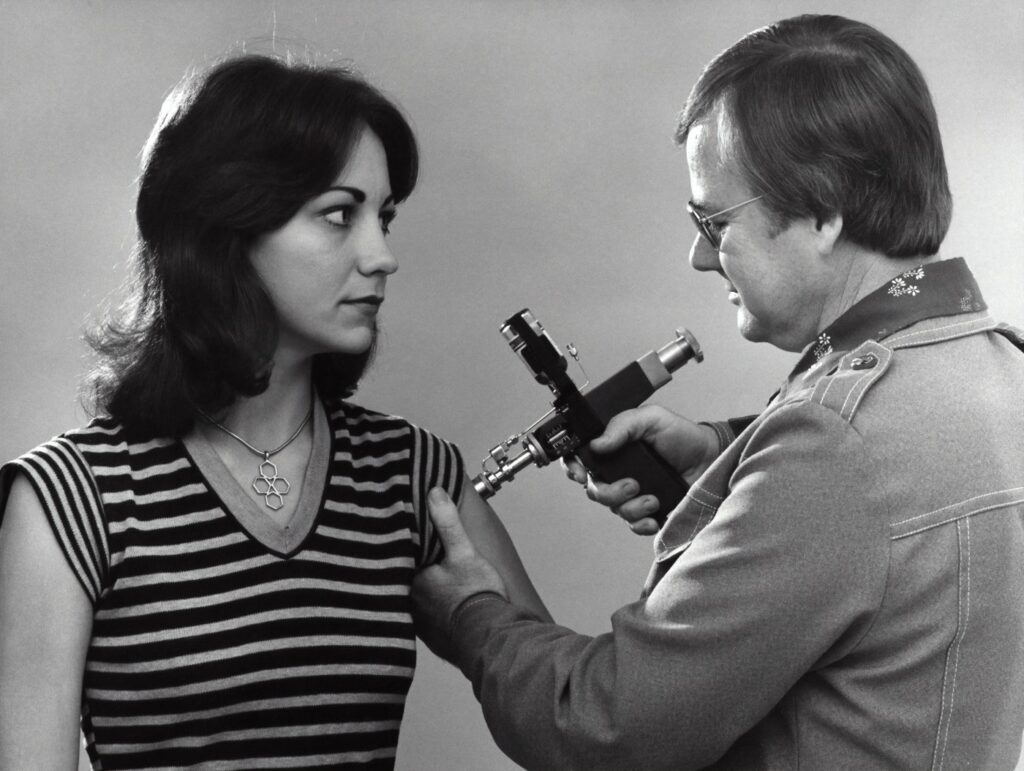 A woman receiving an injection with an old machine